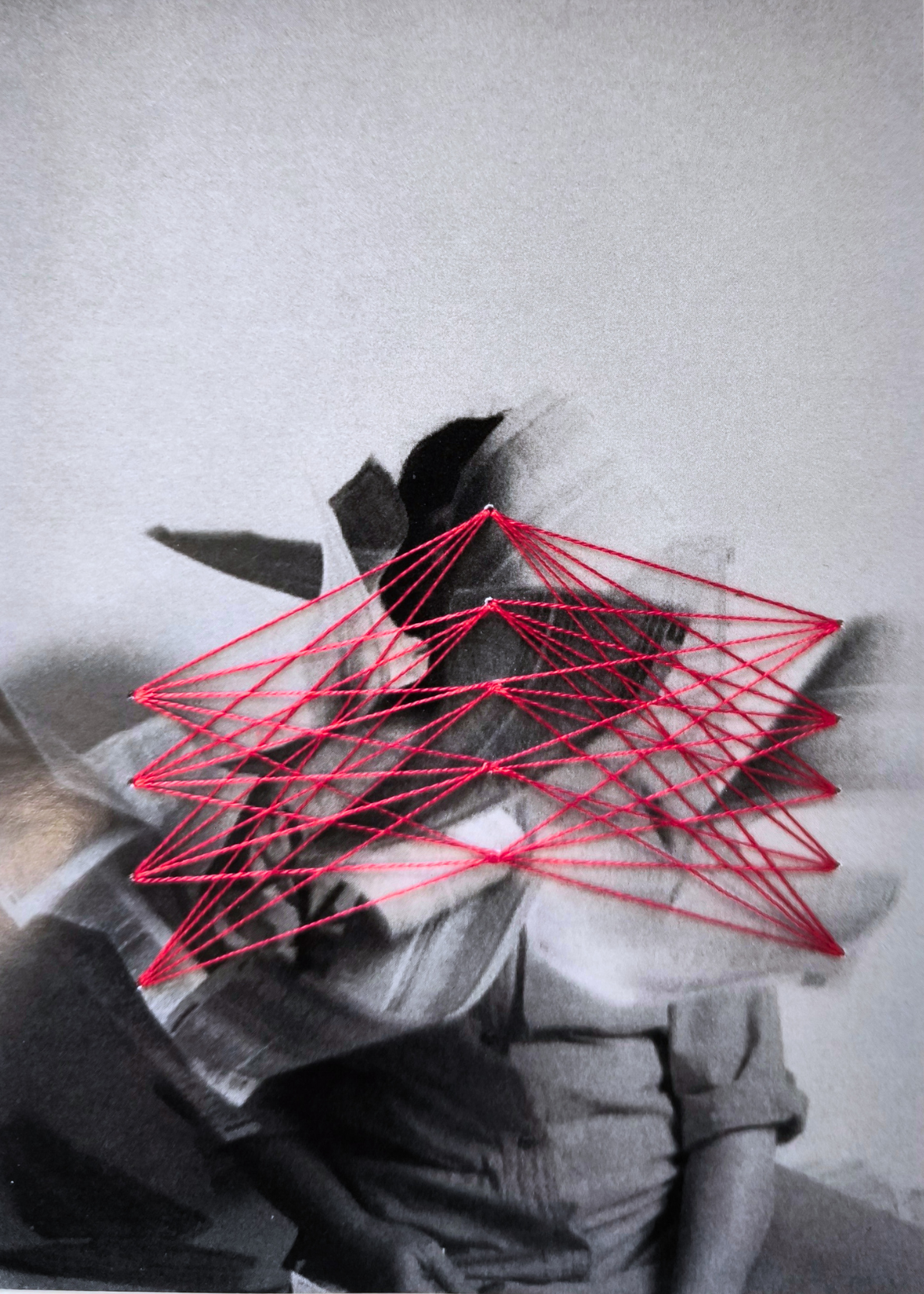 Donna circondata da pagine in movimento, collegate da una trama geometrica ricamata con filo rosso.