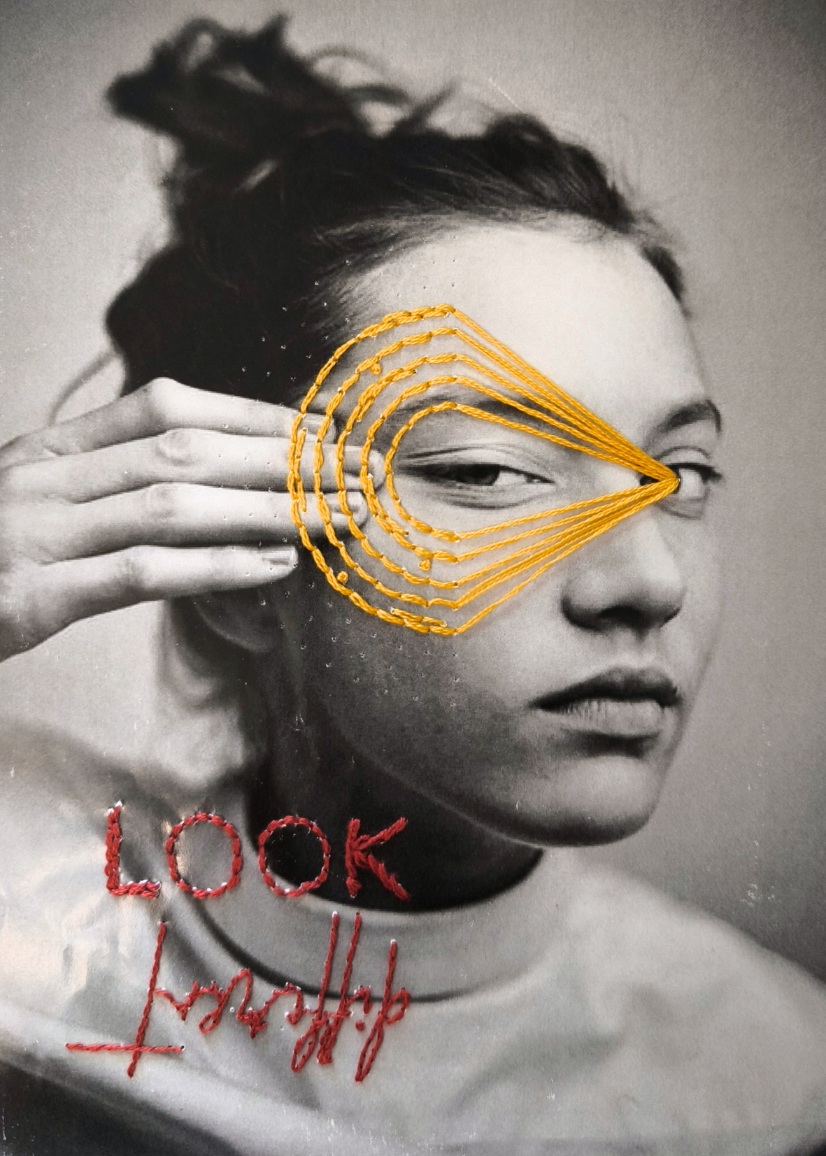 Ritratto con linee gialle ricamate intorno a un occhio e scritte rosse "look different" ricamate sotto il viso.